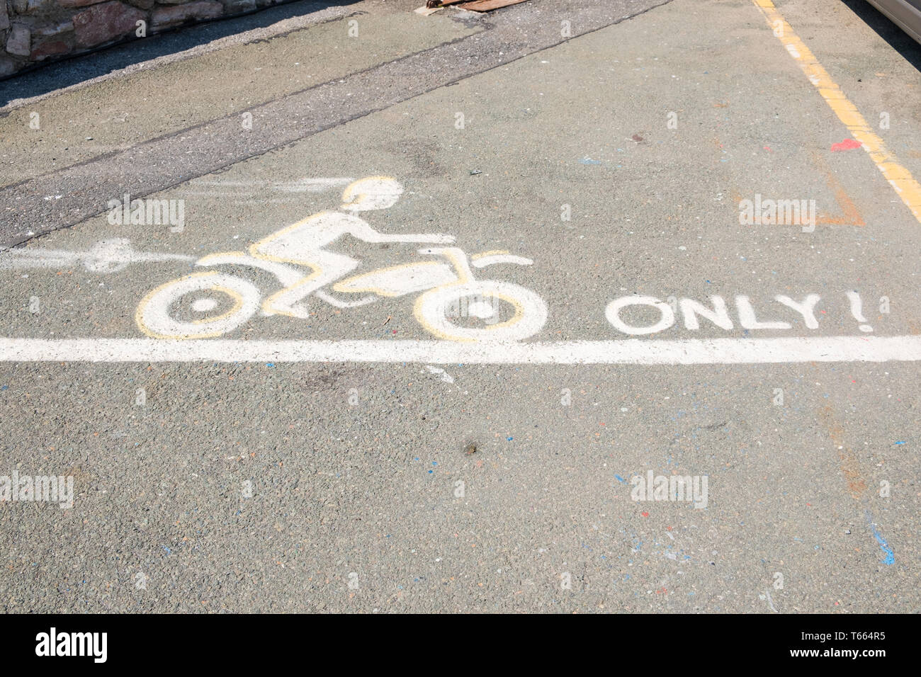 Designated motorcycle parking space with amusing picture of motorbike painted on tarmac Stock Photo