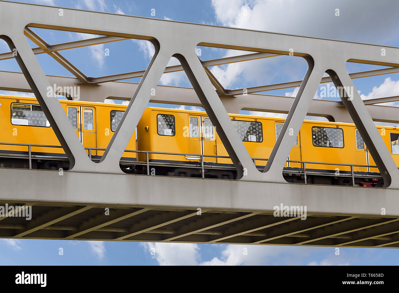 yellow moving train on an iron bridge with blue sky Stock Photo