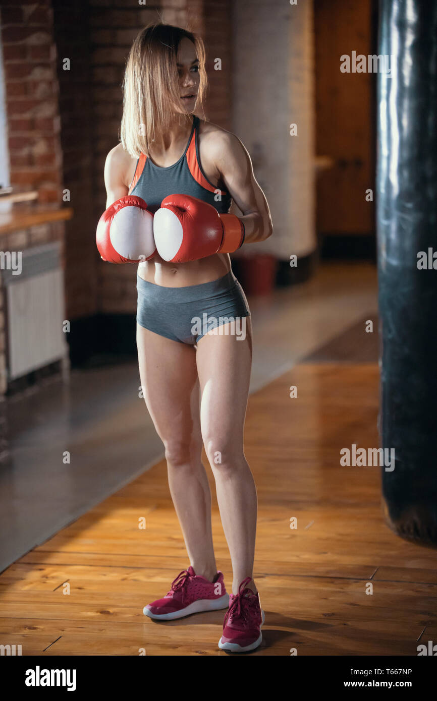 A woman in boxers gloves standing in the gym and posing for the camera Stock  Photo - Alamy