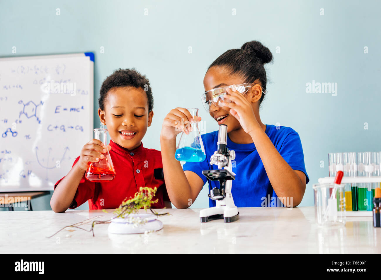Two African American mixed kids tests chemistry lab and holding glass