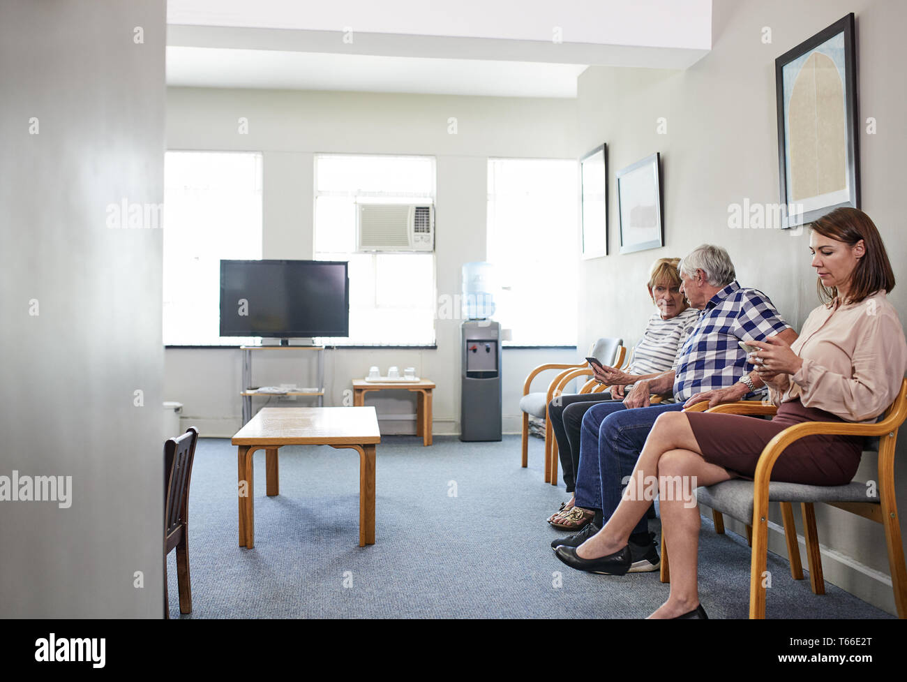 Patients waiting, using smart phones in clinic waiting room Stock Photo ...