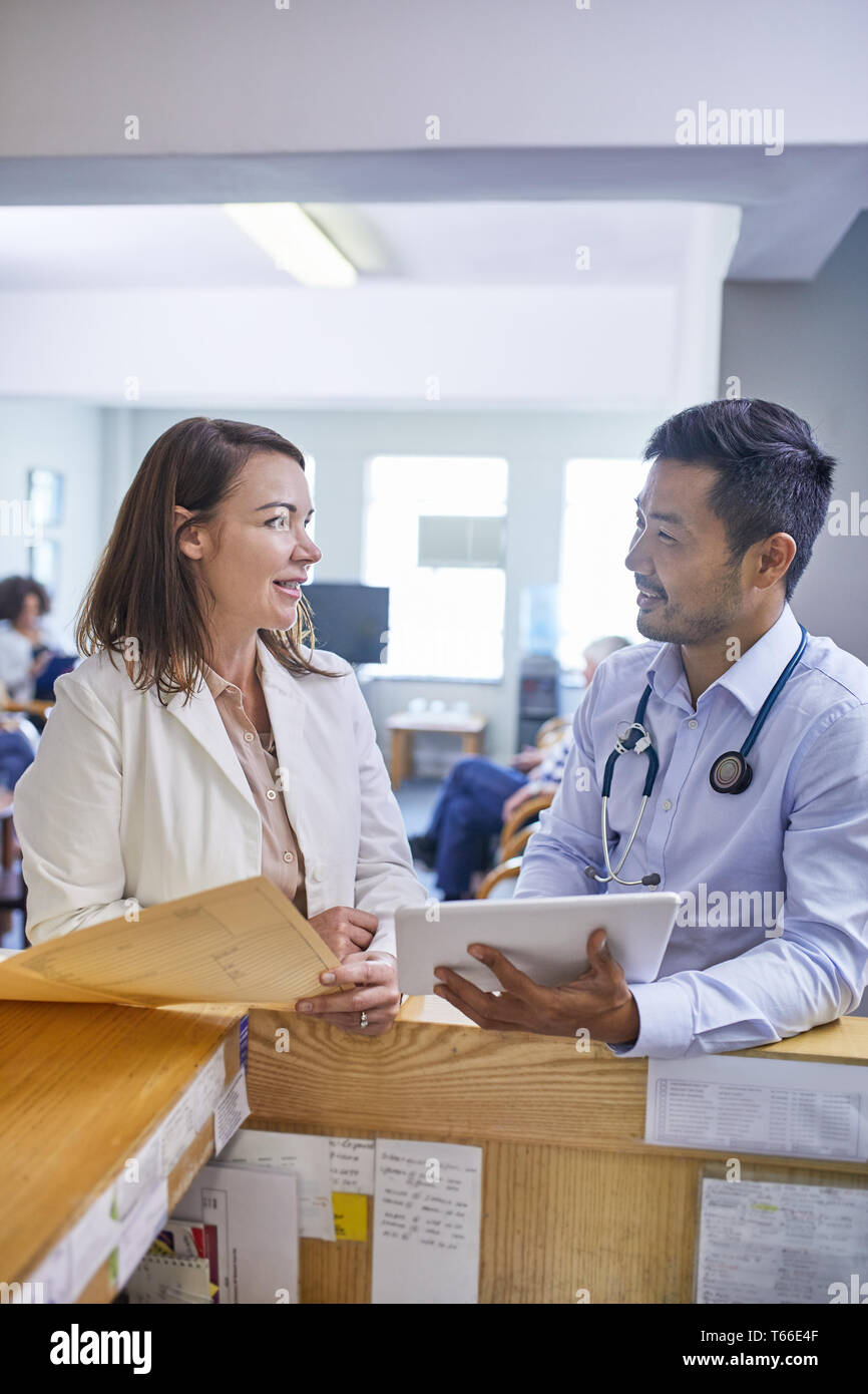 Doctors with digital tablet and medical record talking in clinic Stock Photo