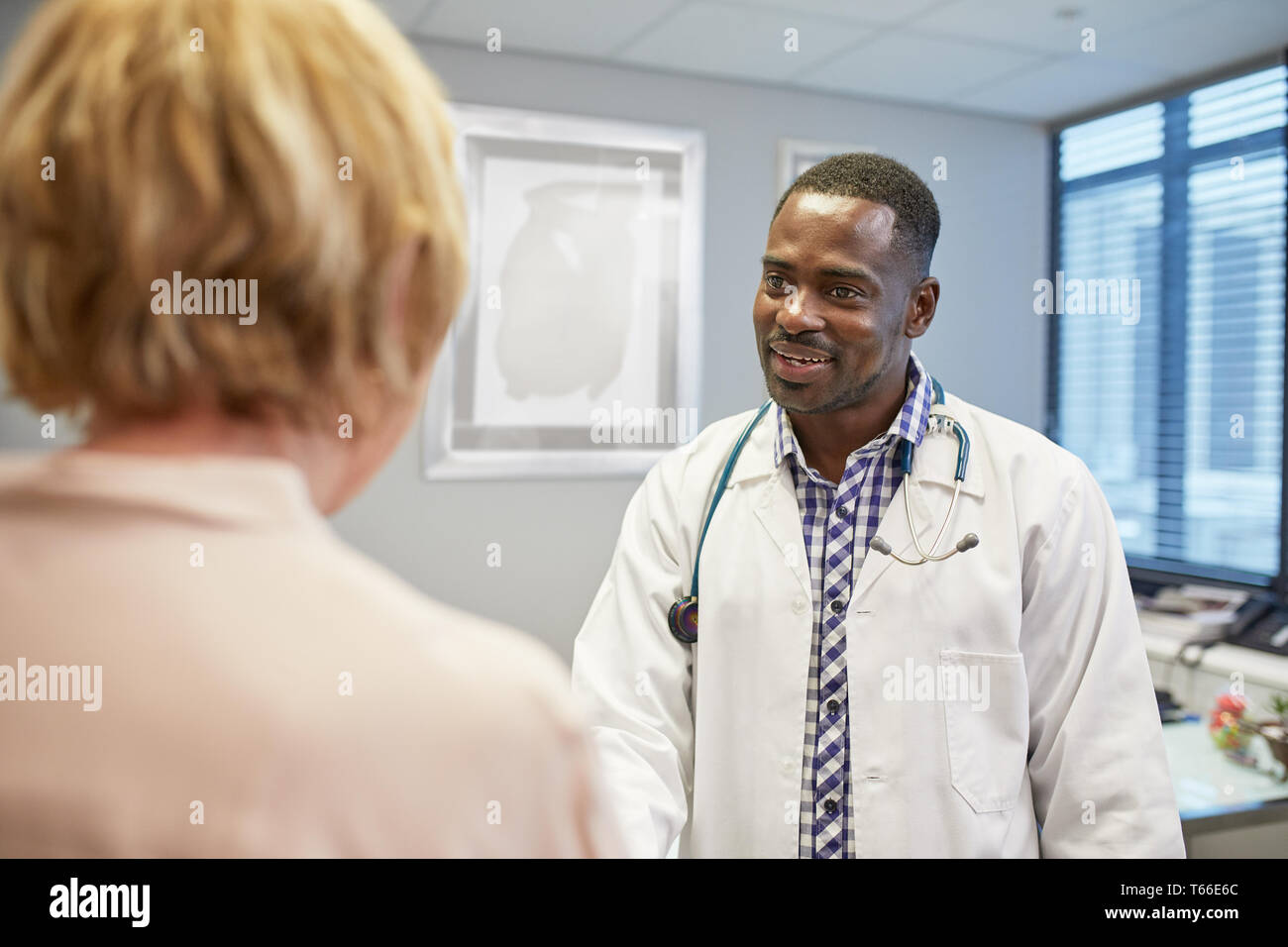 Male doctor talking to senior female patient in doctors office Stock Photo