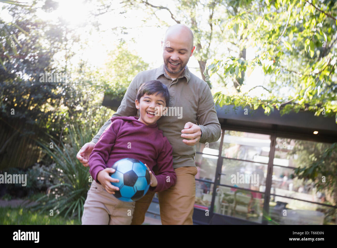 Father and son playing with soccer ball in backyard Stock Photo