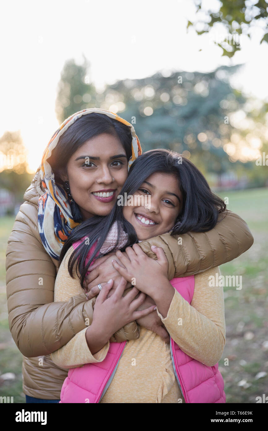 Portrait happy Muslim mother in hijab hugging daughter in park Stock Photo