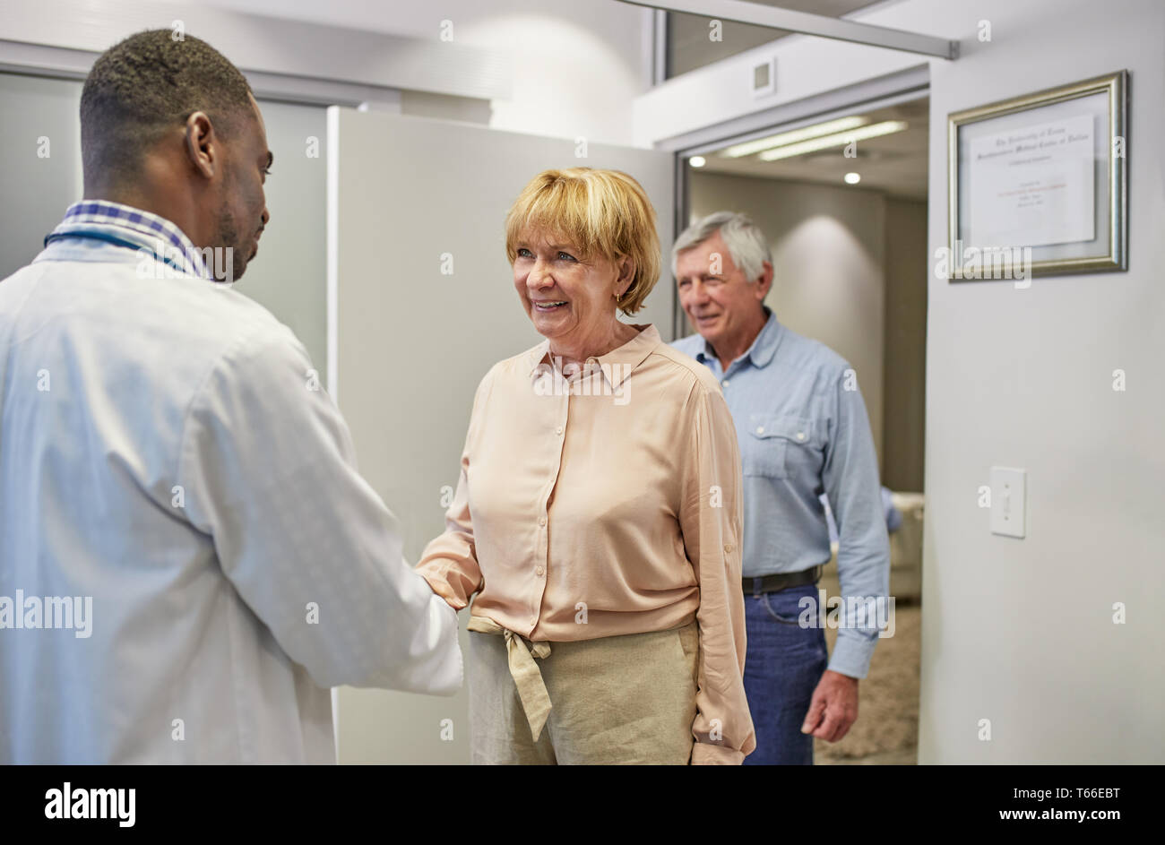 Doctor greeting senior couple in clinic doctors office Stock Photo