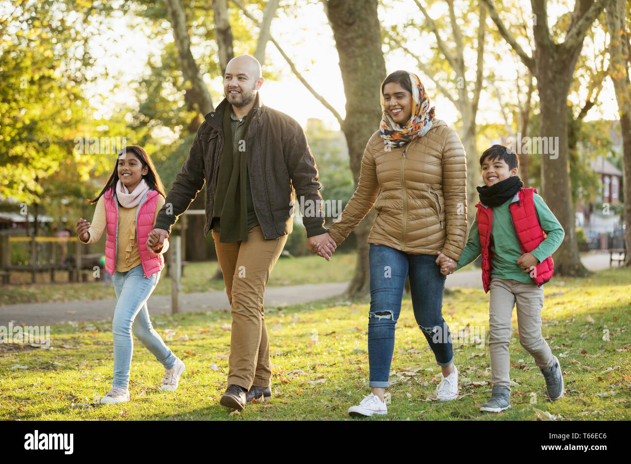 Muslim family holding hands, walking in autumn park Stock Photo