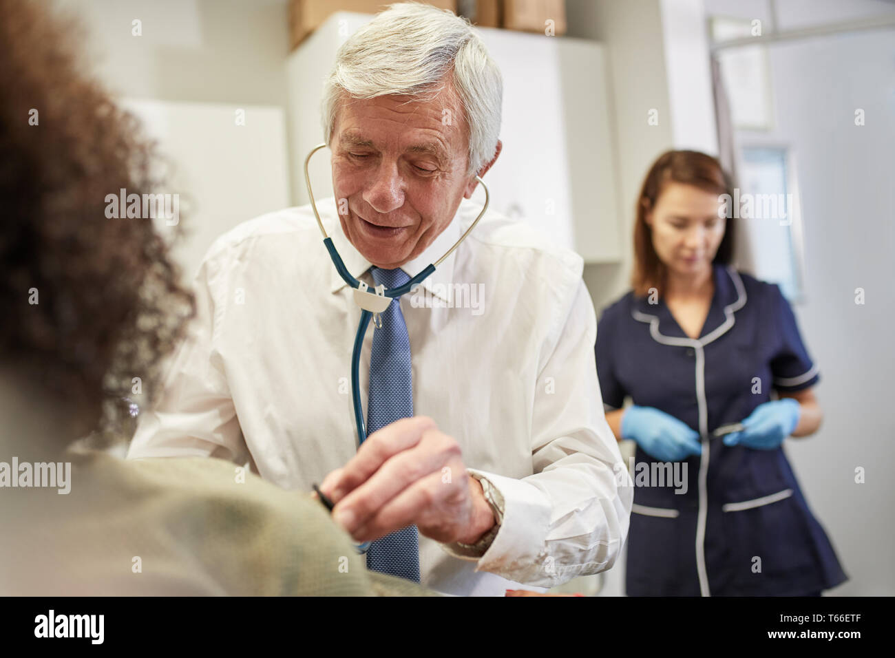 Doctor using stethoscope on client in clinic Stock Photo