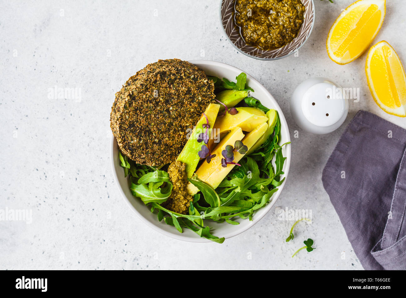 Green avocado salad with green vegan cutlet, arugula and pesto in a gray bowl. Healthy vegan food concept. Stock Photo