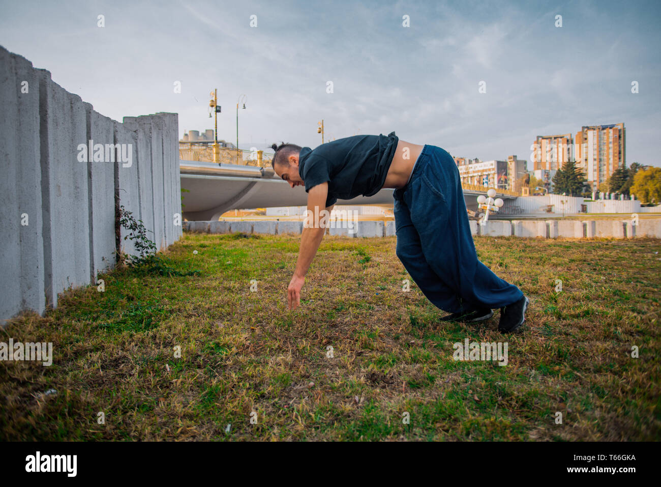 Young man doing one handstand while exercise parkour on the grass Stock Photo