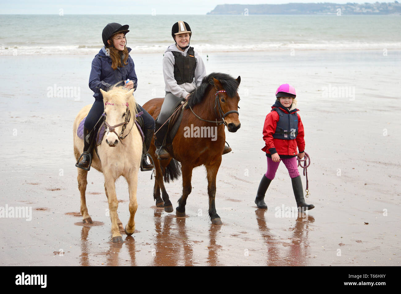 Pony riders on a seaside beach Stock Photo