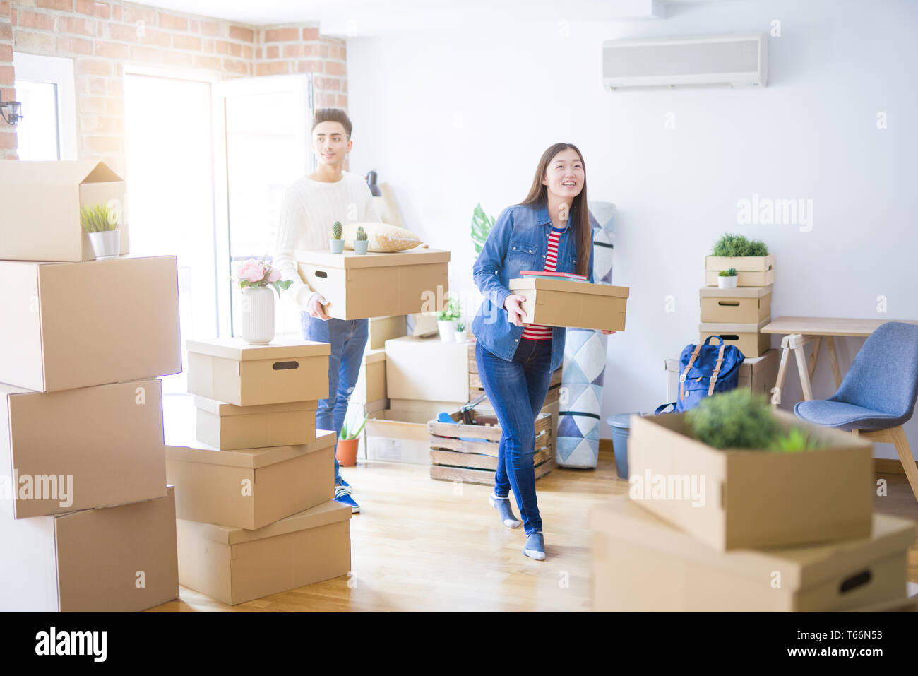 Beautiful young asian couple looking happy holding cardboard boxes ...