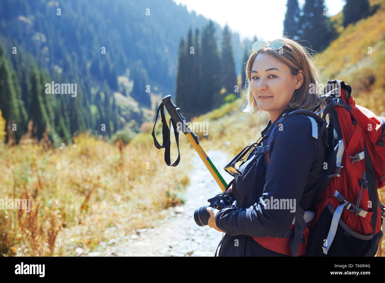 Portrait confident young female photographer backpacking on sunny trail Stock Photo
