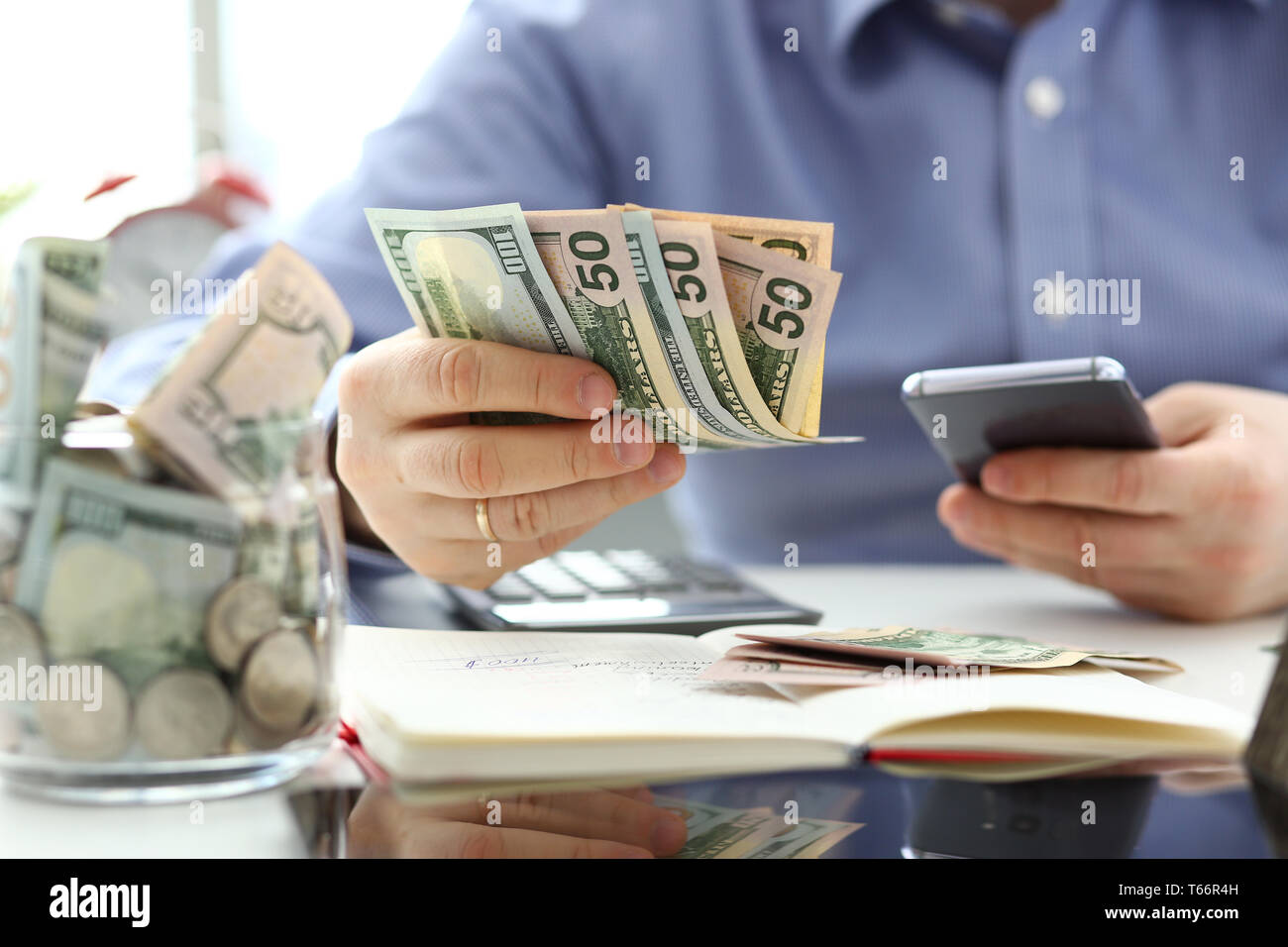Male hand holding pack of banknotes and cellphone Stock Photo