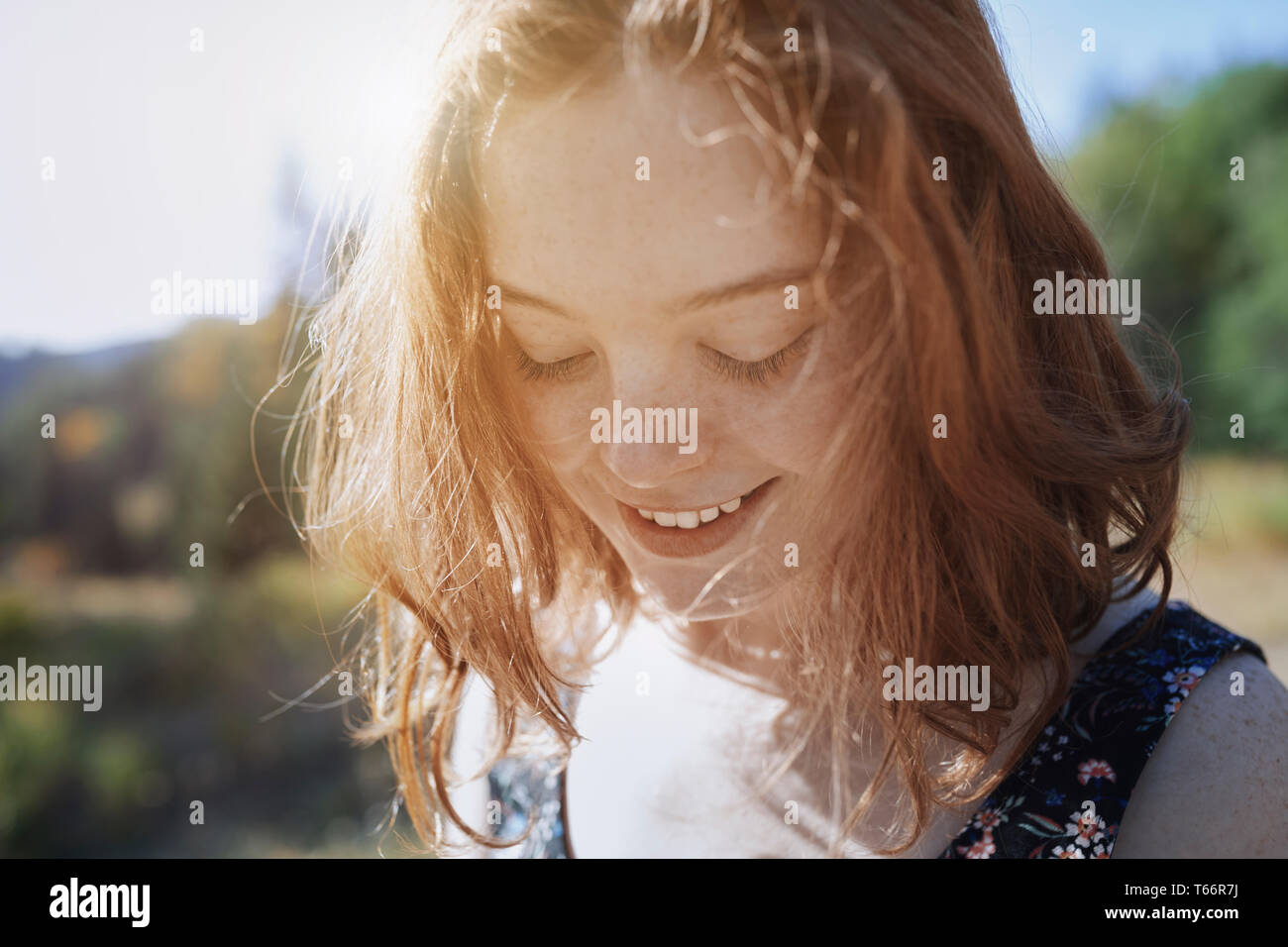 Smiling young woman with freckles looking down Stock Photo