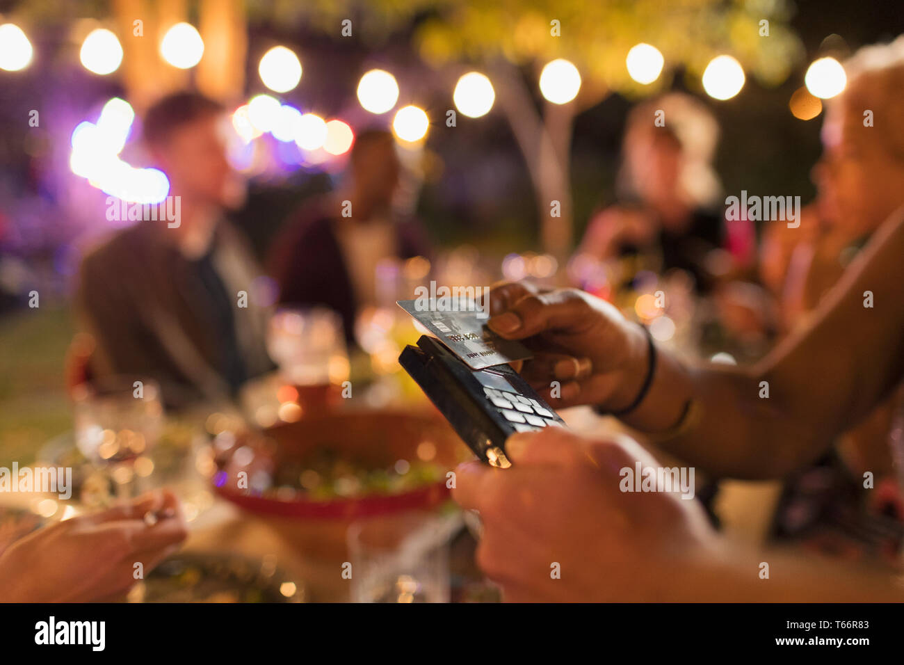 Woman paying for dinner with smart card on patio Stock Photo