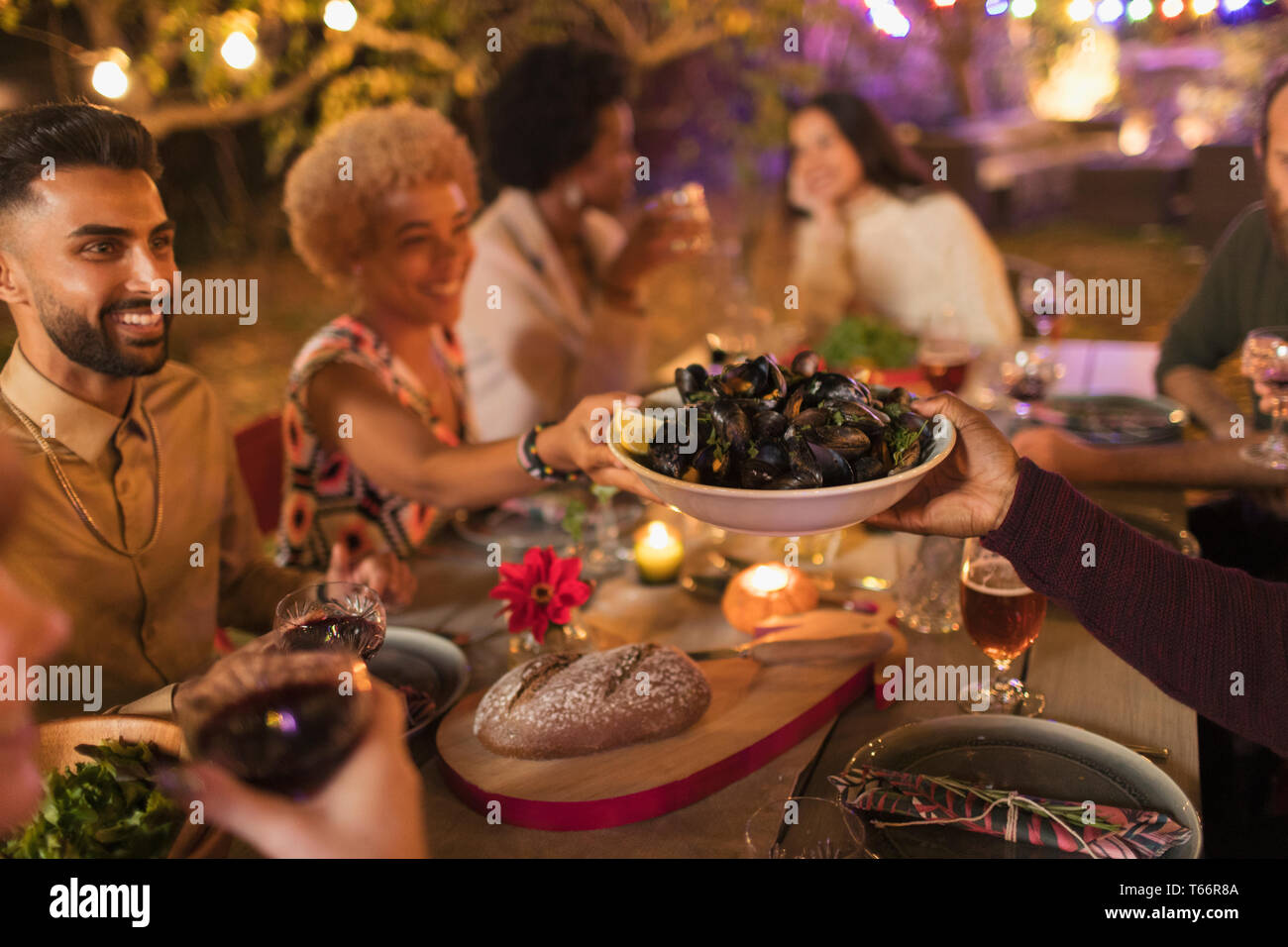 Friends passing mussels, enjoying dinner garden party Stock Photo