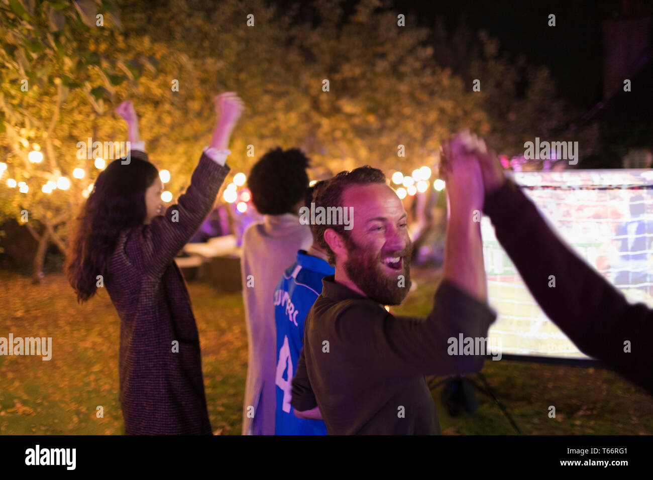 Happy friends cheering, watching sports in backyard Stock Photo