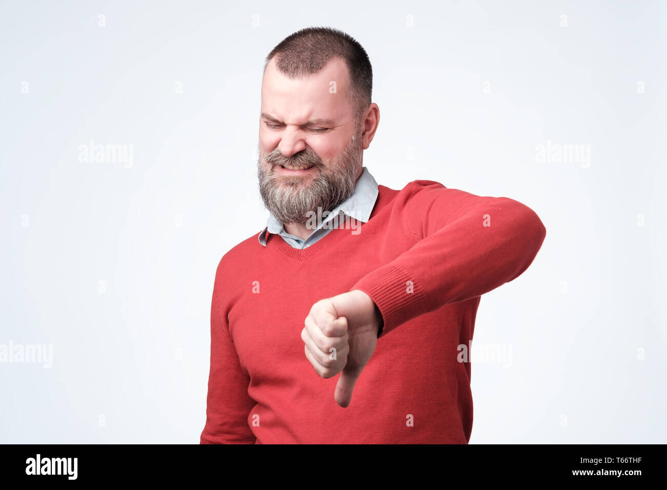 Man in red sweater gives vthumbs down gesture. Stock Photo