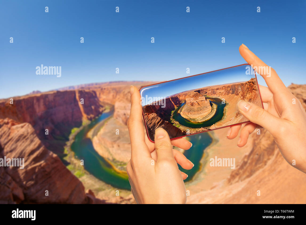 Hands hold smartphone taking photo horse shoe canyon, Utah USA Stock Photo