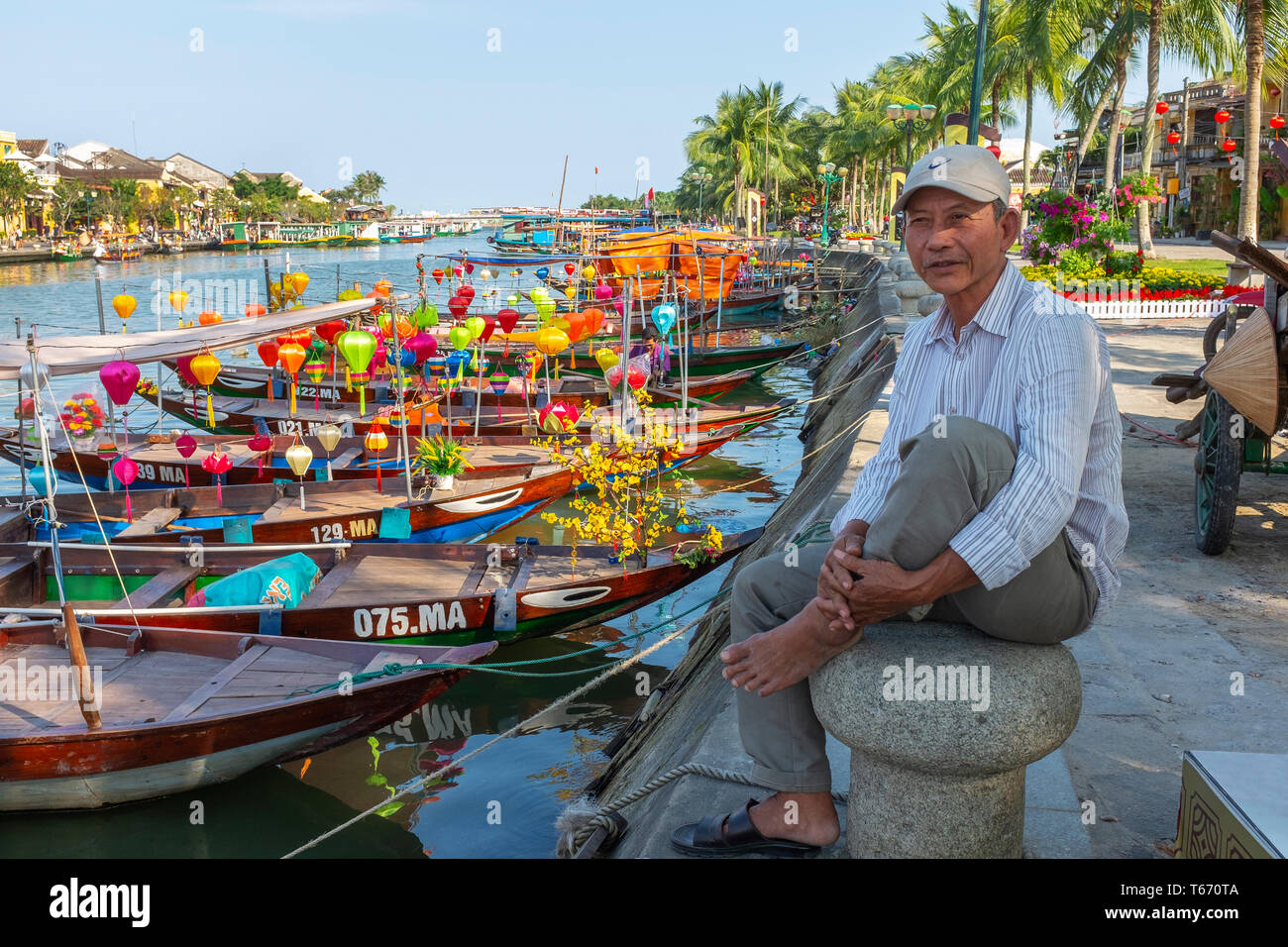 Local Vietnamese fisherman sitting on a capstan at the side of the harbour on Son Thu Bon river, Hoi An, Quang Nam Provence, Vietnam, Asia Stock Photo