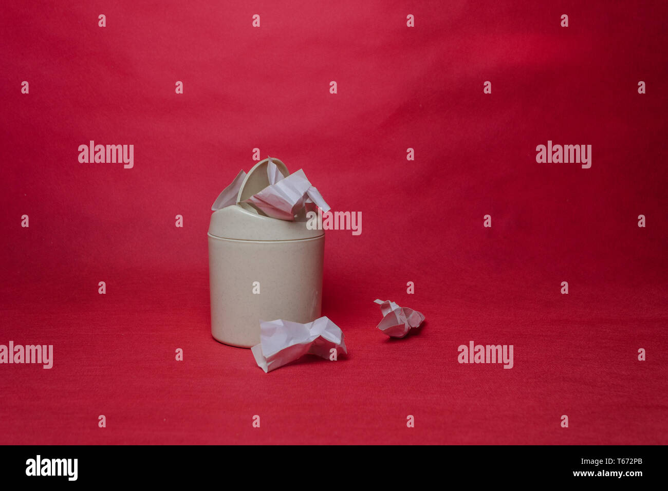 Light trash bin on a red background. Closeup of crumpled sheets of ...