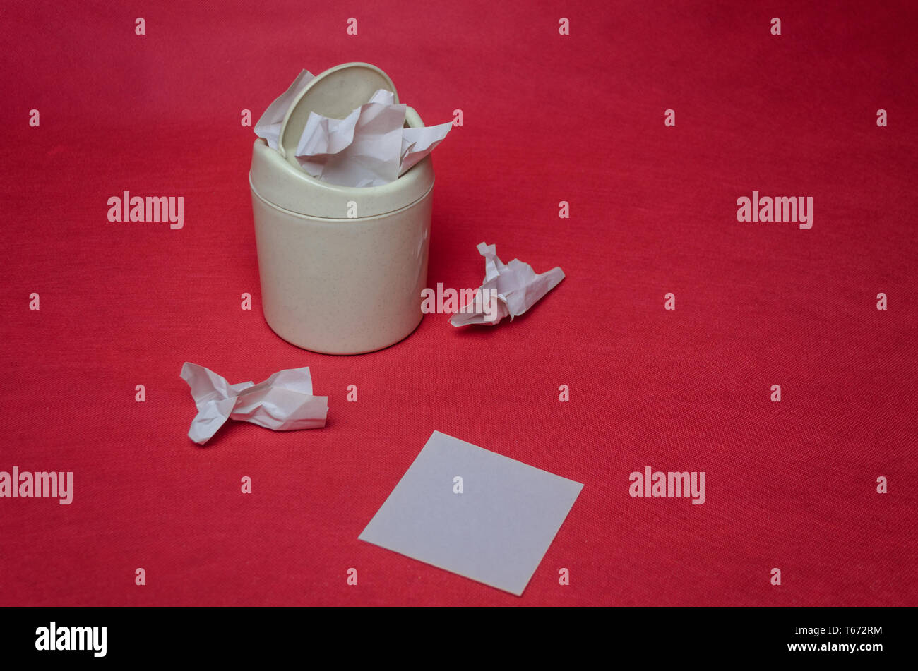 Light trash bin on a red background. Closeup of crumpled sheets of