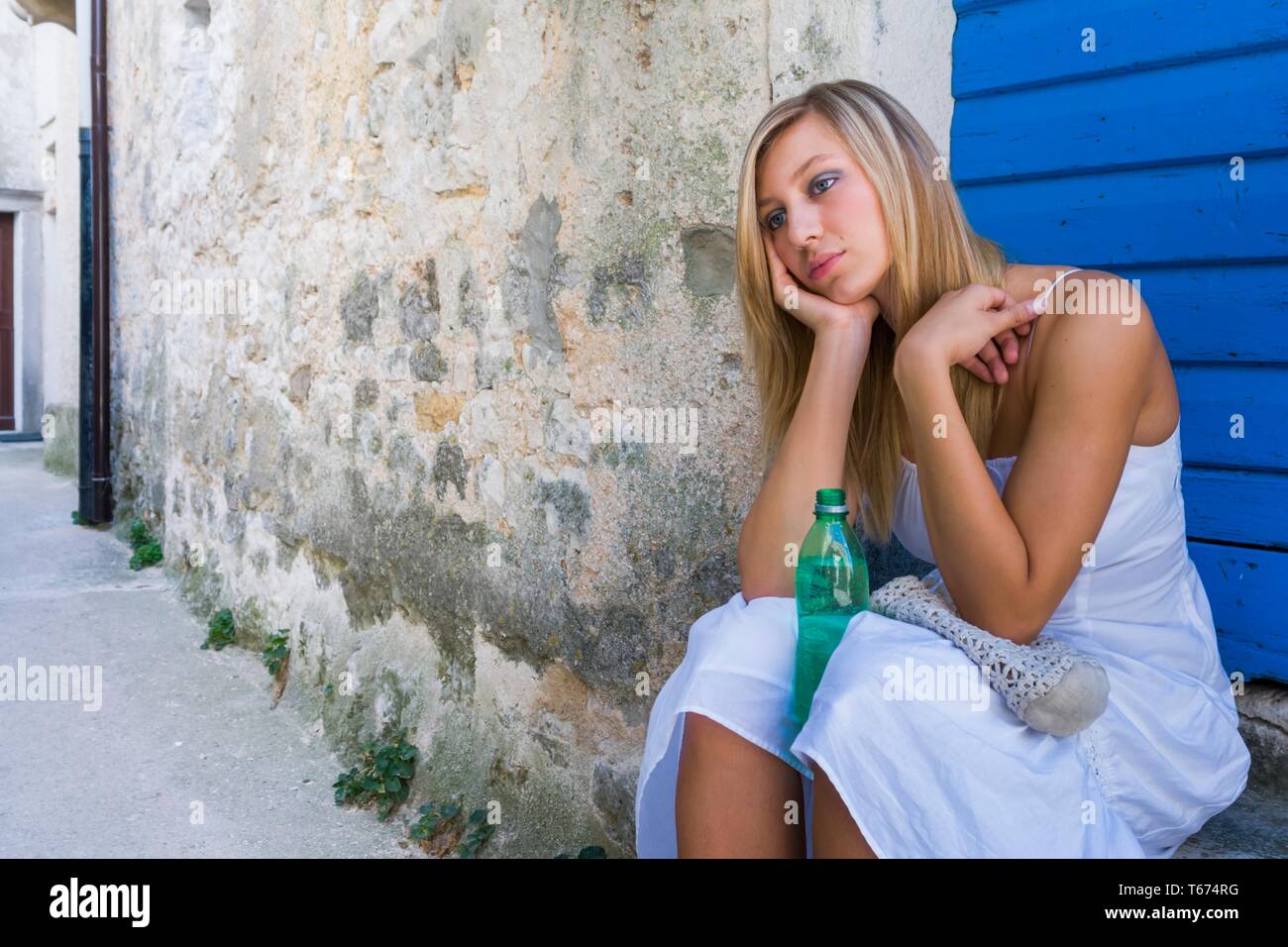 Blonde Haired Pretty Teen Girl Wearing Long White Dress Is Sitting