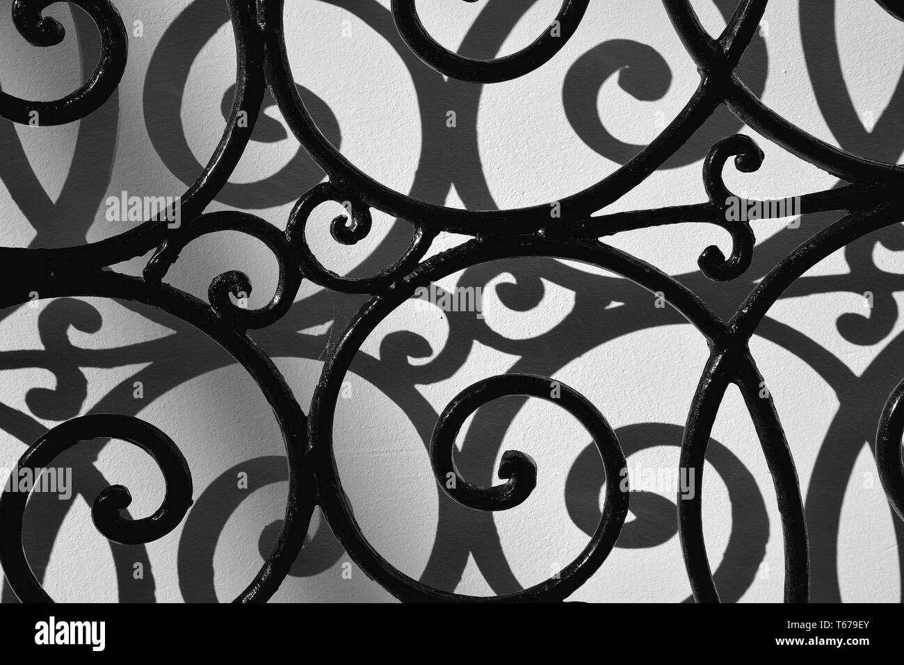 Curved iron bars casting shadows on wall. Stock Photo