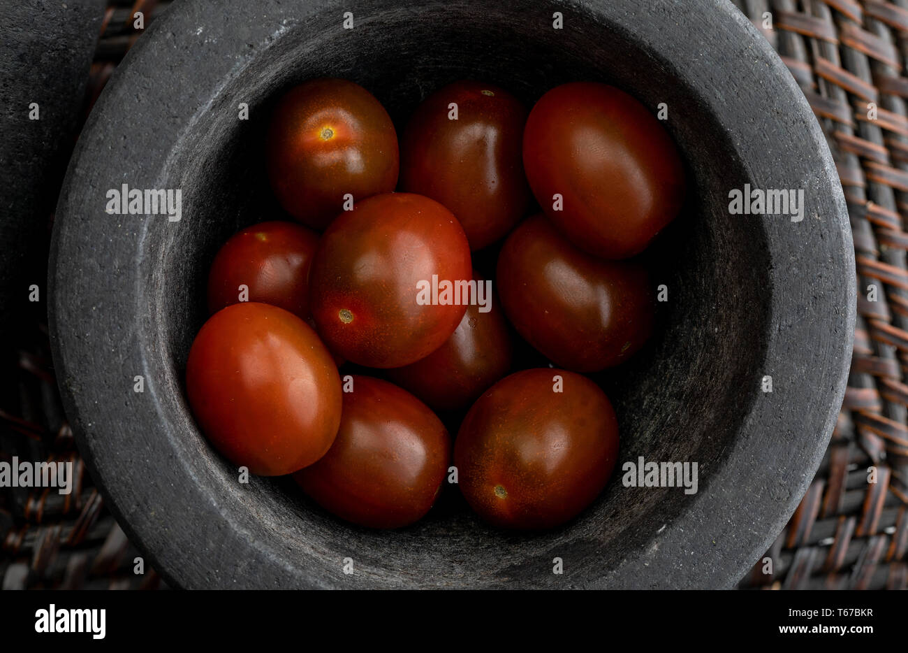 Cherry tomatoes mini Kumato. In stone mortar. Rustic appearance Stock