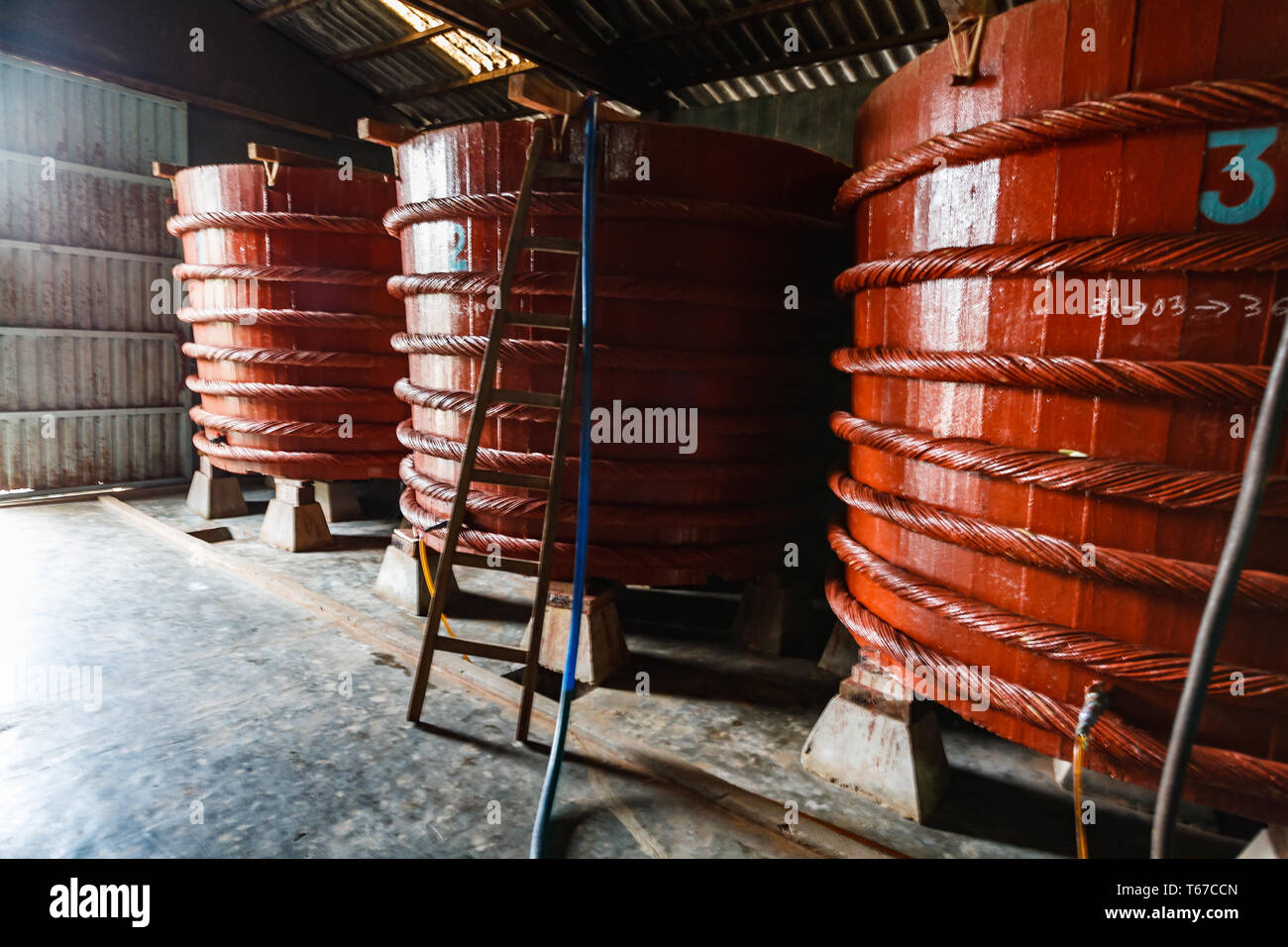 Closeup of three colorful red wooden barrels, with traditional fish sauce condiment fermenting inside a factory Stock Photo