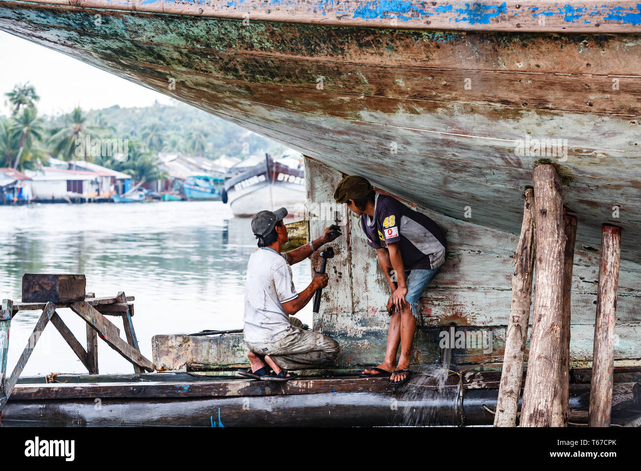 closeup of man with hammer working on keel of a hull of a boat Stock