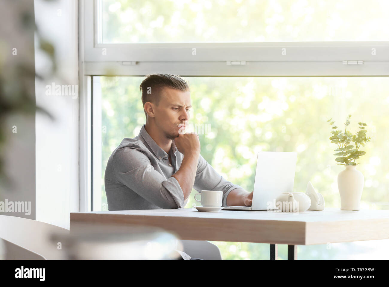 Troubled freelancer working on laptop in cafe Stock Photo
