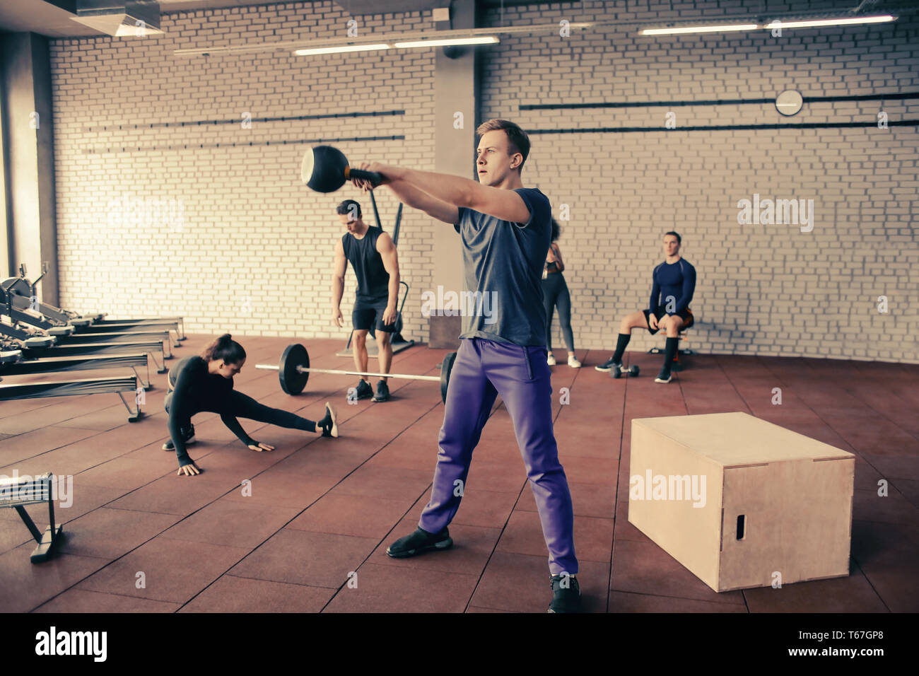 Athletic man doing exercises with kettlebell in modern gym Stock Photo