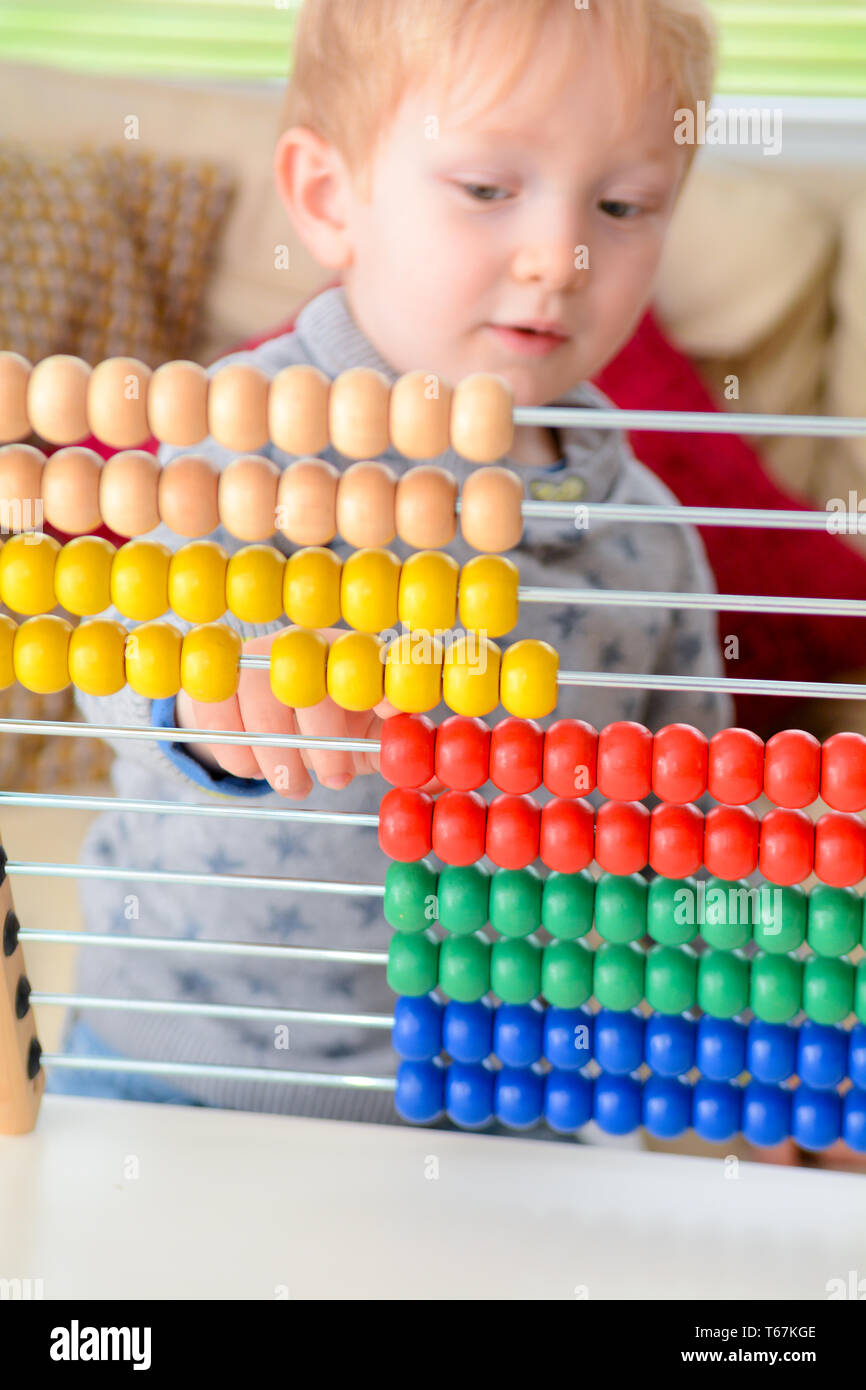 Child learning to count. Young boy using an abacus to learn maths Stock