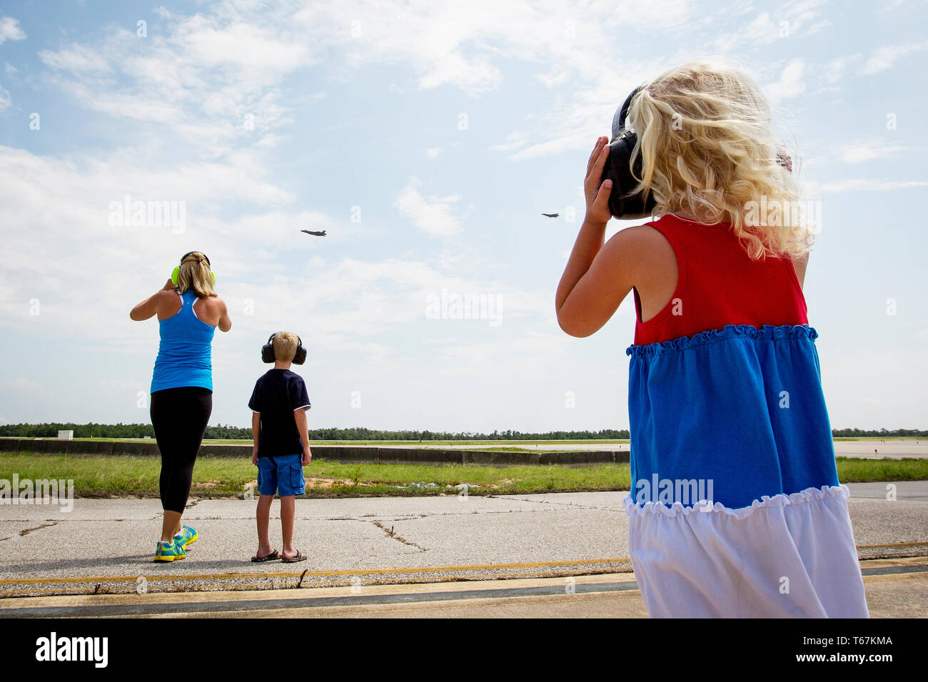 As US pilot Brad Turner does a fly-by on his first mission in the new F-35A Fighter Jet, his wife Whitney, daughter Addison (4) and their son Chase (10) cheer on from the tarmac at the Eglin Air Force Base. Stock Photo
