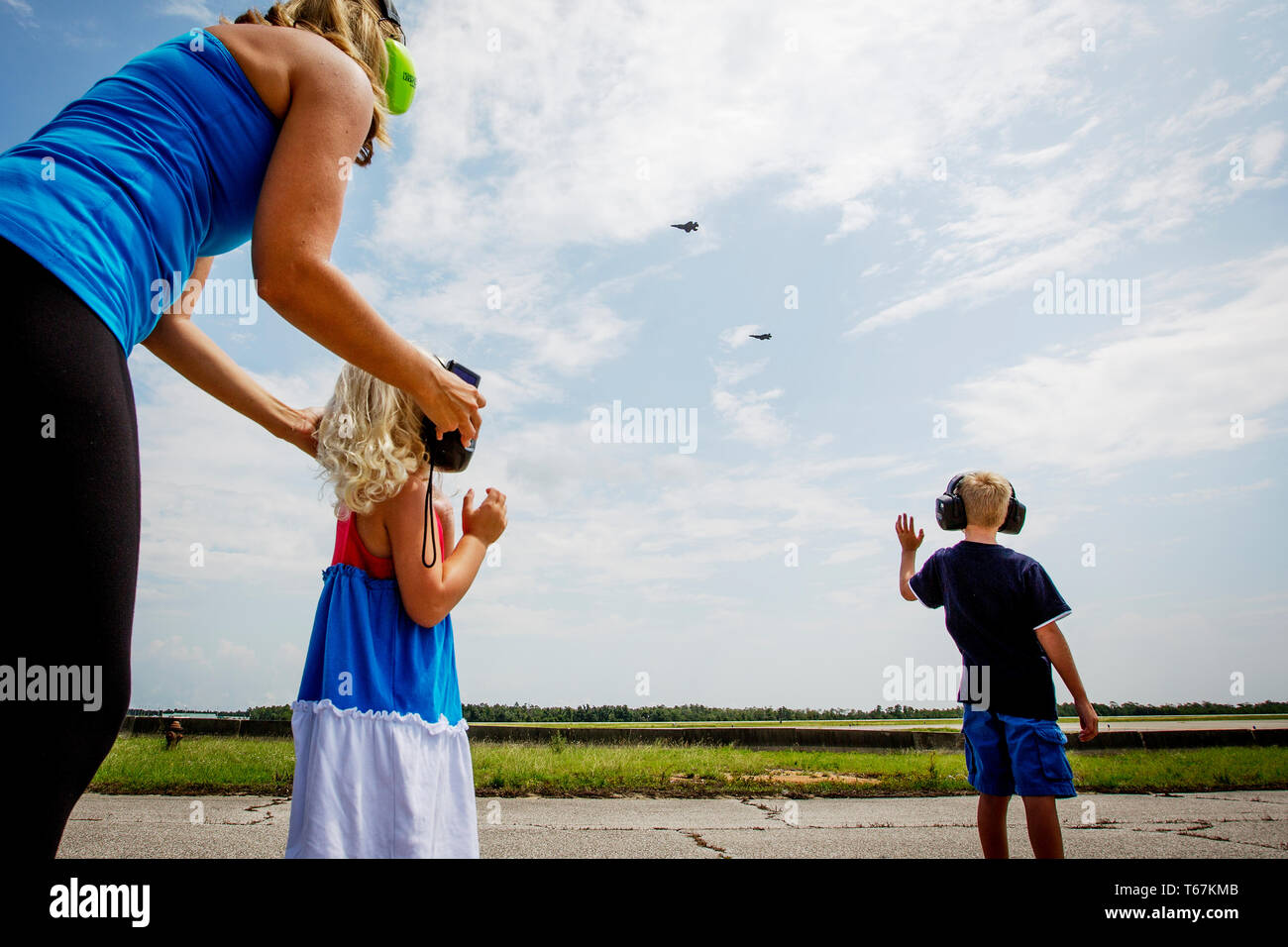 As US pilot Brad Turner does a fly-by on his first mission in the new F-35A Fighter Jet, his wife Whitney, daughter Addison (4) and their son Chase (10) cheer on from the tarmac at the Eglin Air Force Base. Stock Photo