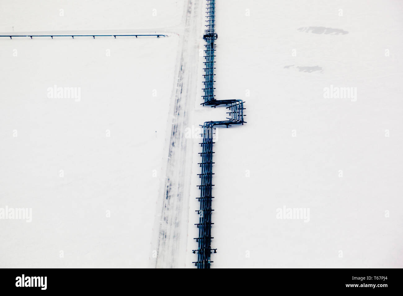 Oil pipeline and iceroad leading from the ConocoPhillips oilwells in Alpine, connecting to the Pump station 1 on the Alyeska Pipeline in Prudhoe Bay, the northern start of the Trans-Alaska Pipeline System. Stock Photo