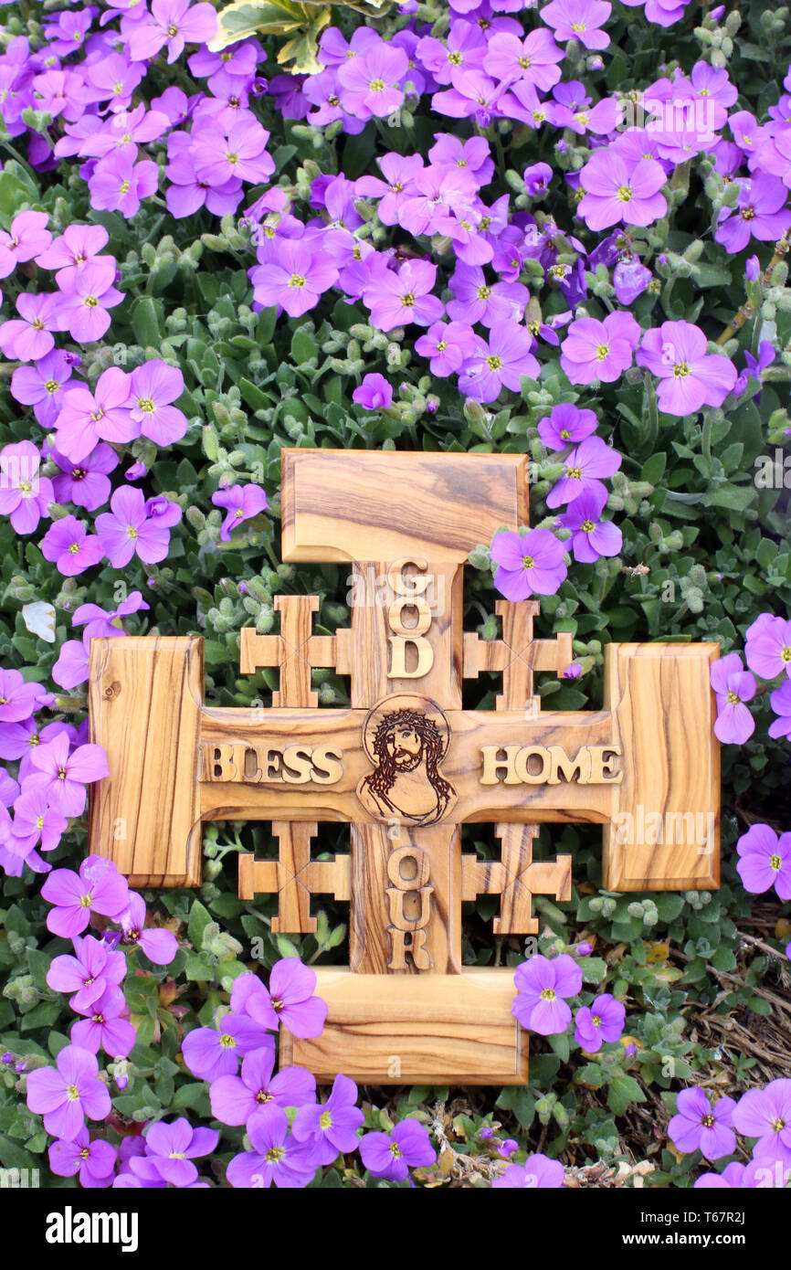 Croix de Jérusalem en bois d'olivier représentant Jésus-Christ sur un parterre de violettes. Stock Photo