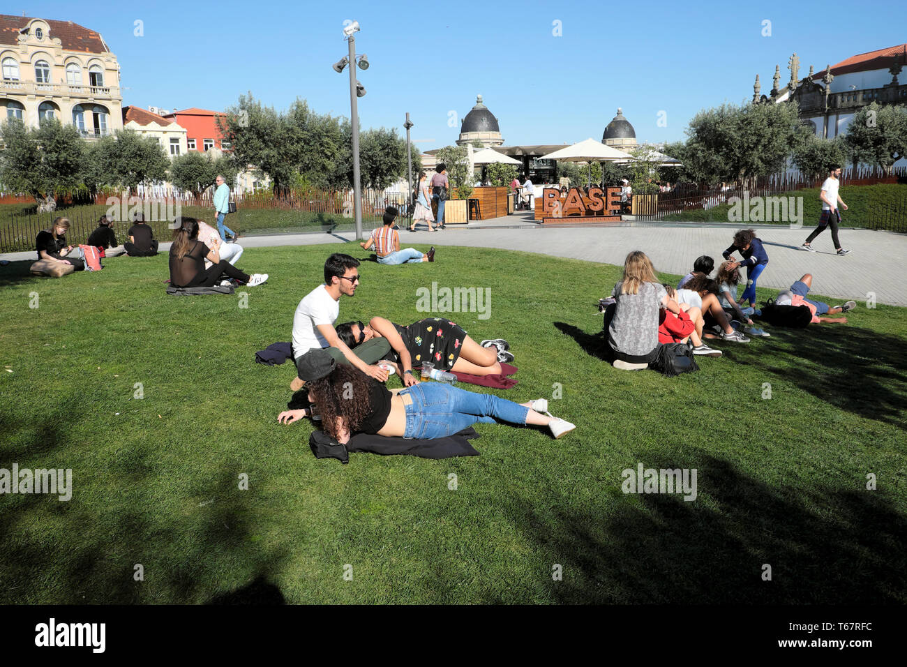View of olive trees & people students relaxing sitting on the lawn by Base  Porto cafe in the Jardim das Oliveiras, Praça de Lisboa Porto KATHY DEWITT  Stock Photo - Alamy