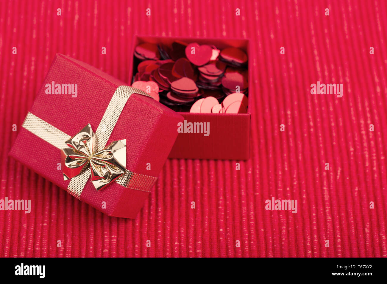 Red hearts confetti on fabric background Stock Photo - Alamy