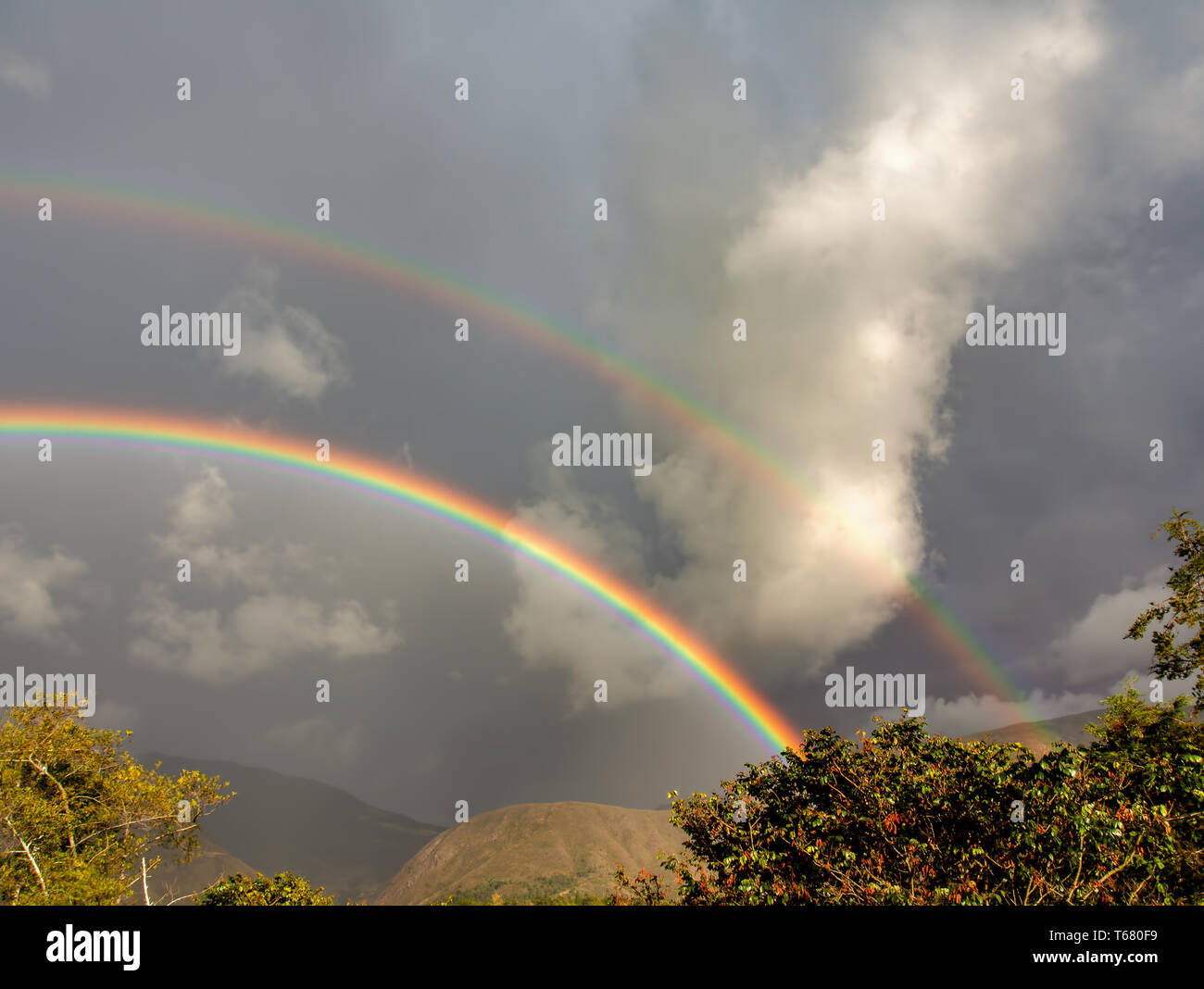 Landscape with two rainbows on a stormy sky. Captured at the Andean mountains of central Colombia. Stock Photo