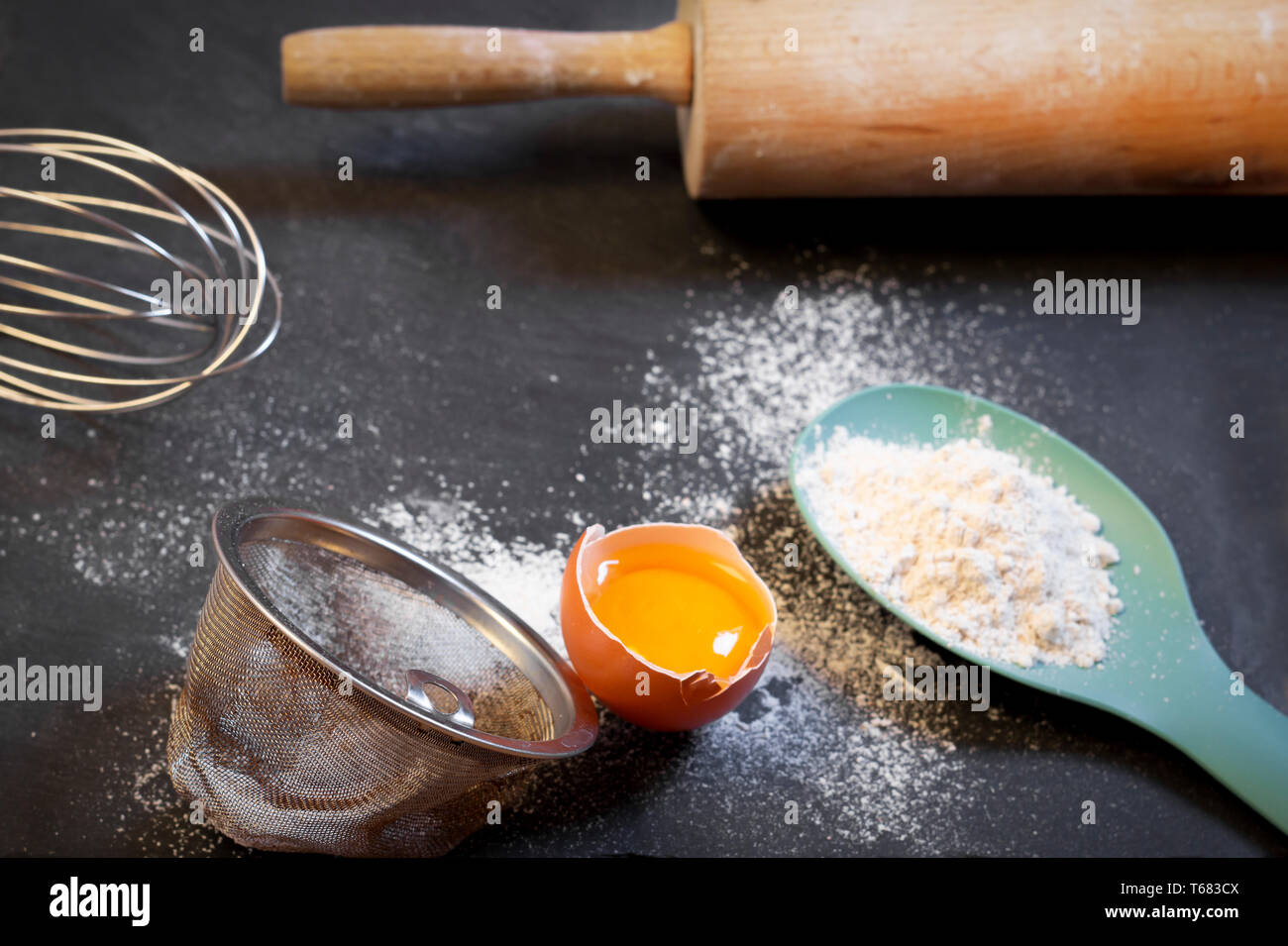 Baking ingredients - flour, egg yolk and eggshells on black chalkboard Stock Photo