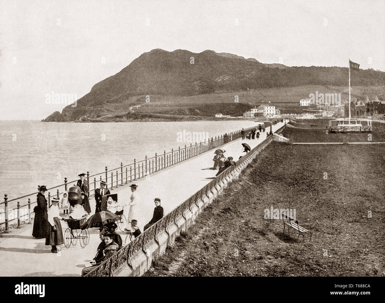 Late 19th Century view of the promenade in Bray, a coastal town in north County Wicklow, Ireland situated just south of Dublin on the east coast. When the Dublin and Kingstown Railway opened in 1834 and was extended as far as Bray in 1854. With the coming of the railway, the town grew to become a seaside resort with hotels and residential terraces built in the vicinity of the seafront. Stock Photo