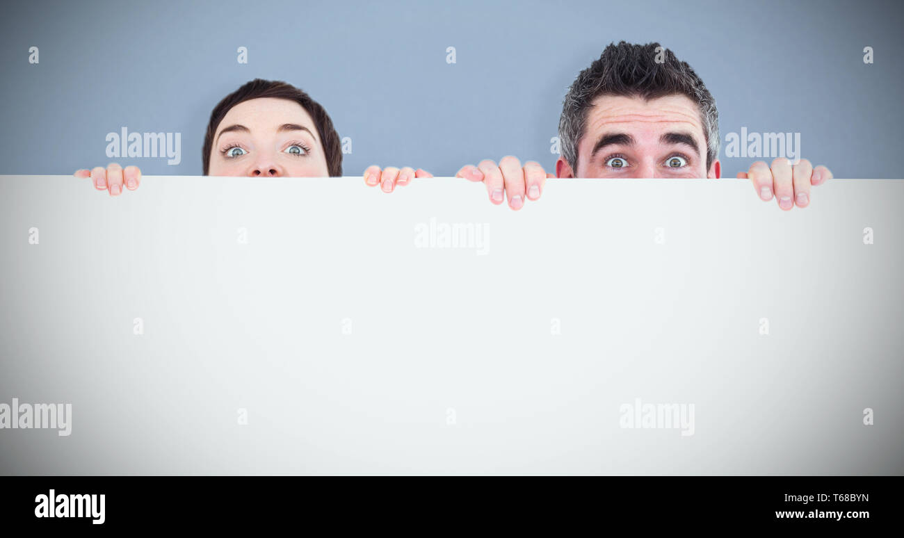 Composite image of man and woman hiding behind a white board with room for  copy space Stock Photo