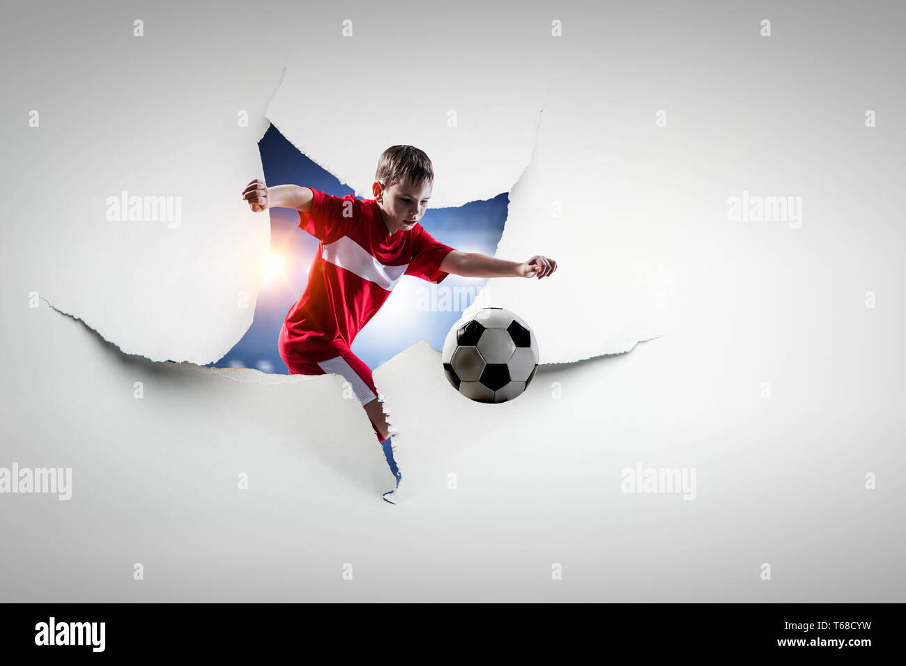 Paper torn hole effect and a kid playing soccer. Mixed media Stock