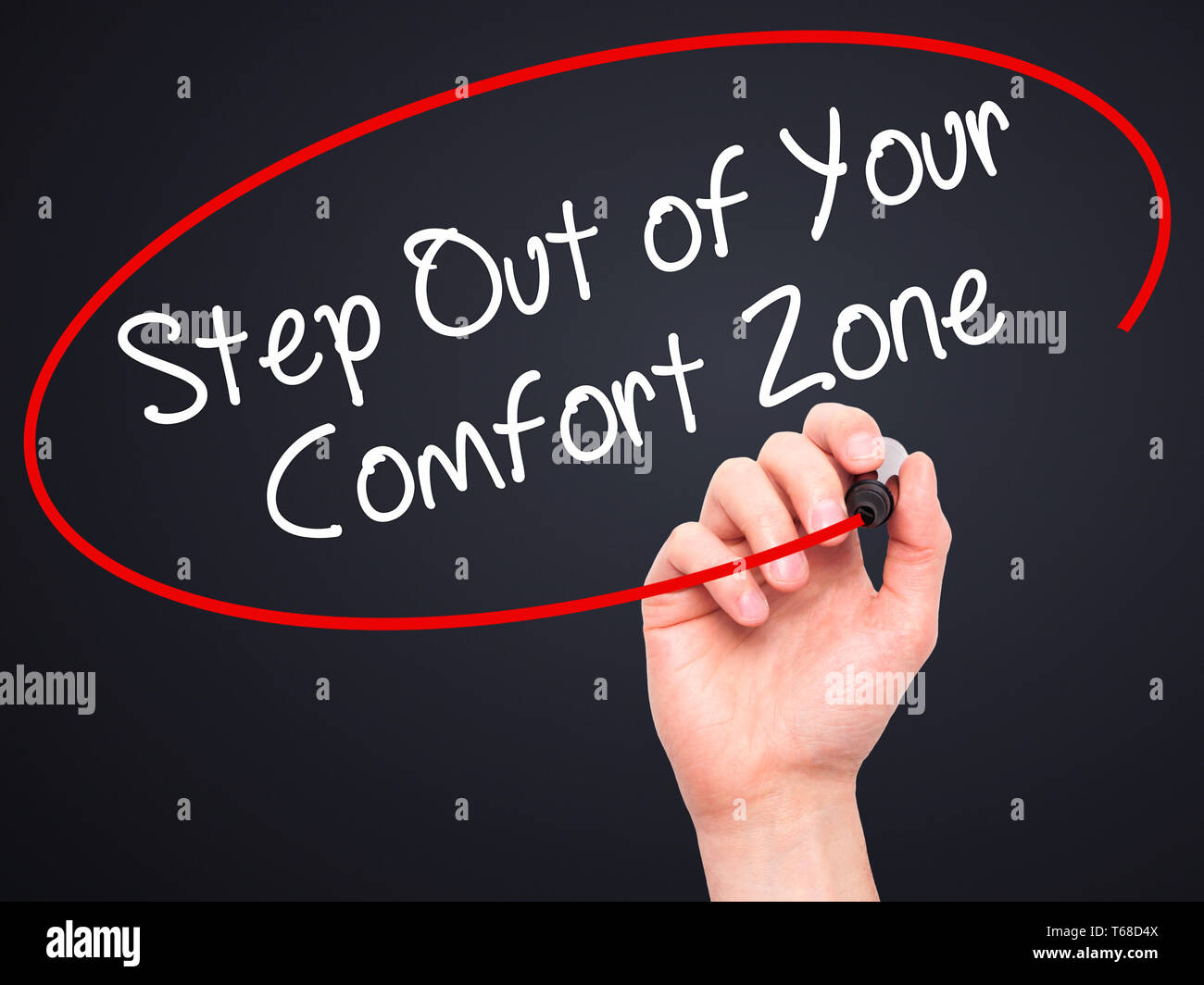 Man Hand writing Step Out of Your Comfort Zone with black marker on visual screen. Stock Photo