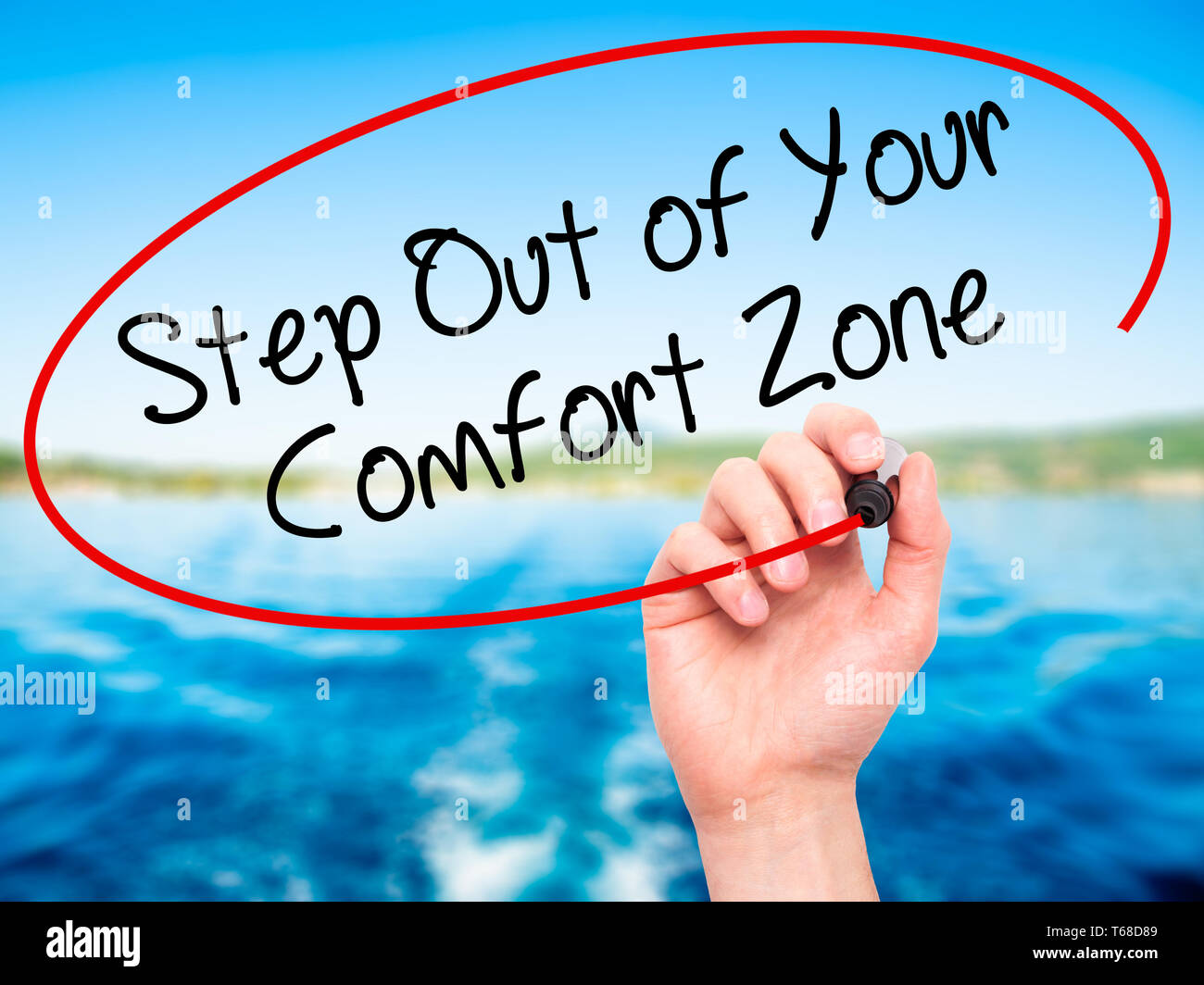 Man Hand writing Step Out of Your Comfort Zone with black marker on visual screen. Stock Photo