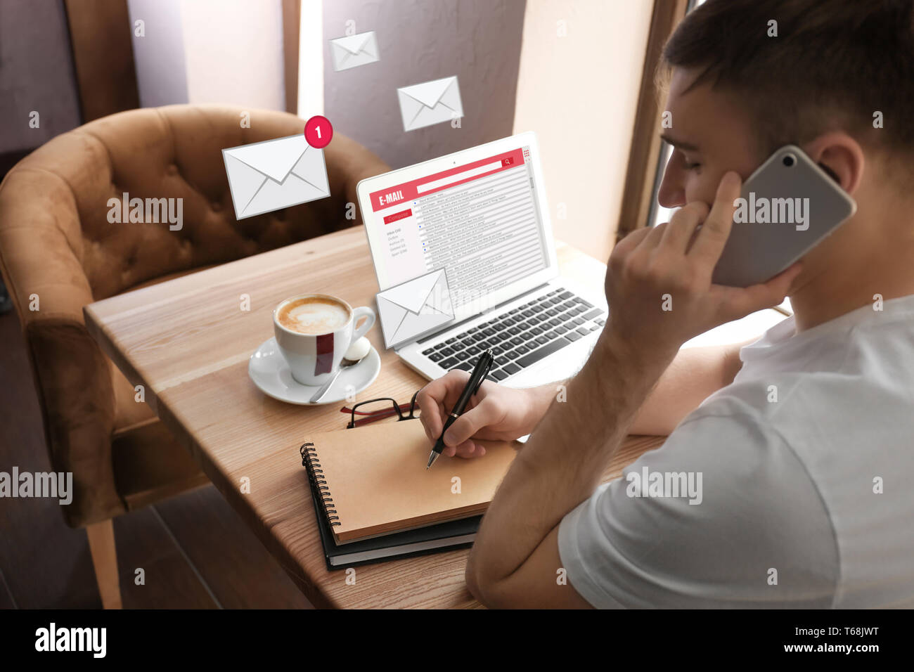 Young man talking on mobile phone while checking an email in cafe Stock Photo