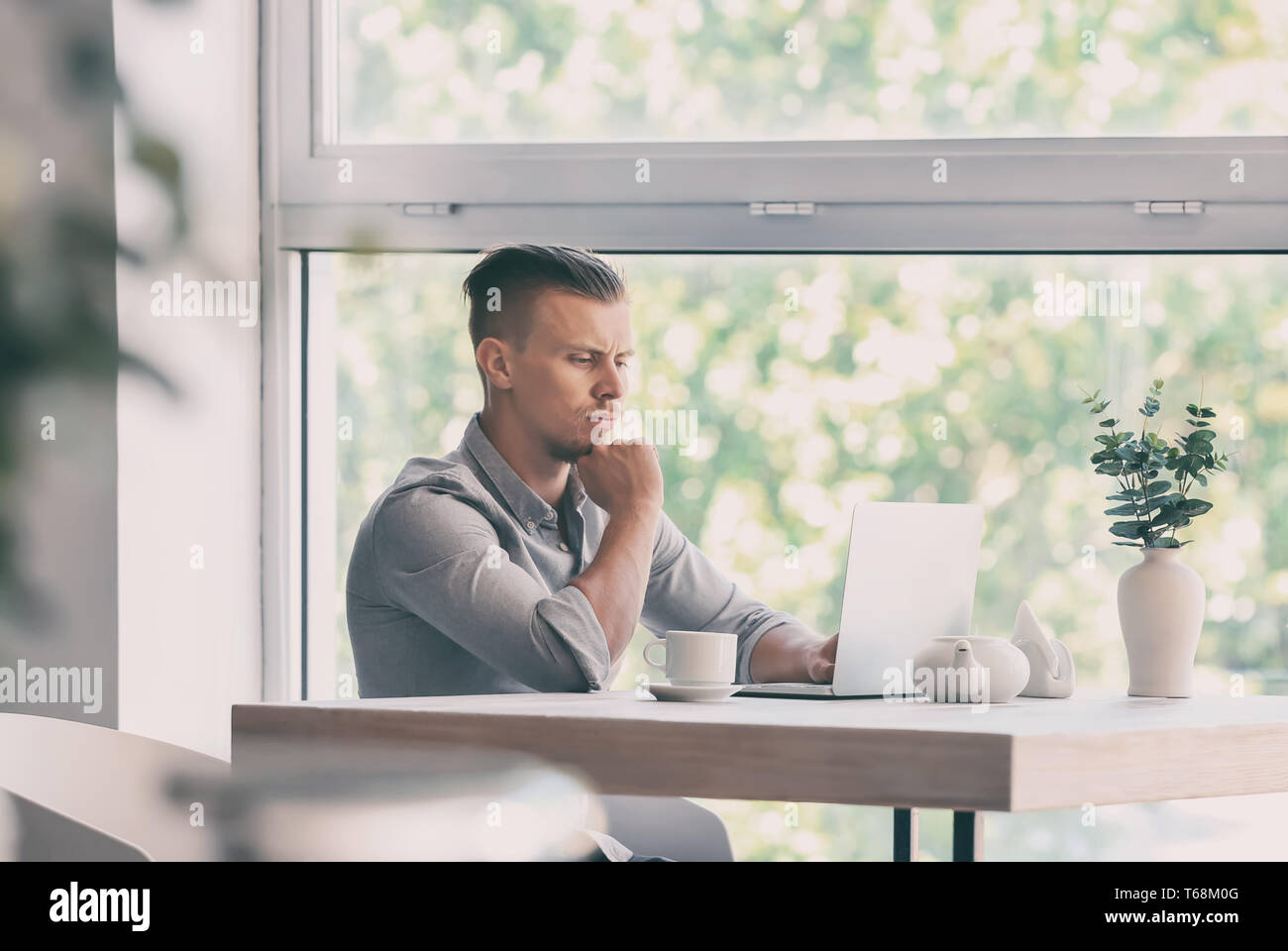 Troubled freelancer working on laptop in cafe Stock Photo